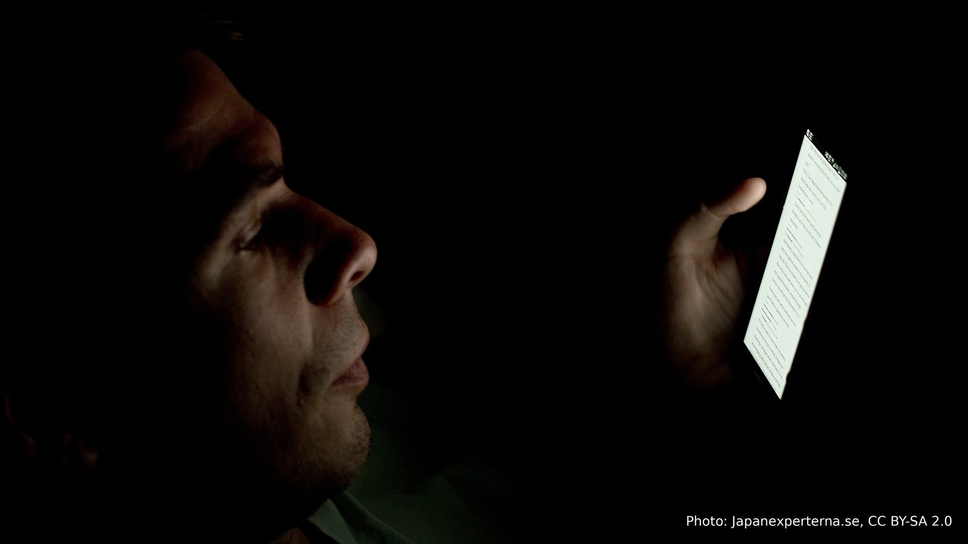 A man alone in the dark, lit only by his phone