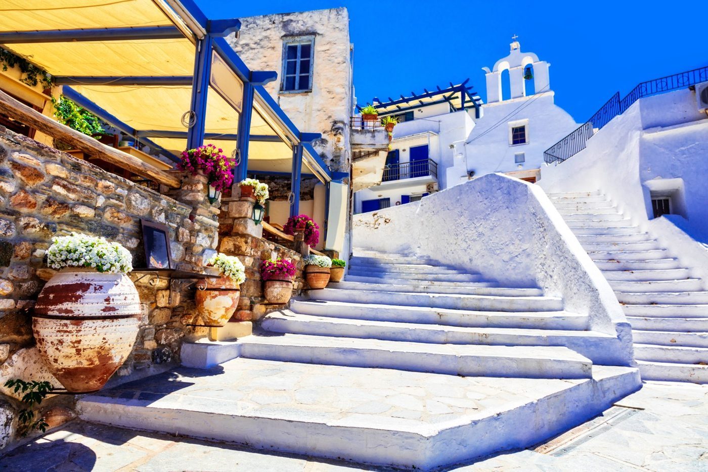 Whitewashed steps, flowers and a blue-domed chapel in a Naxos village